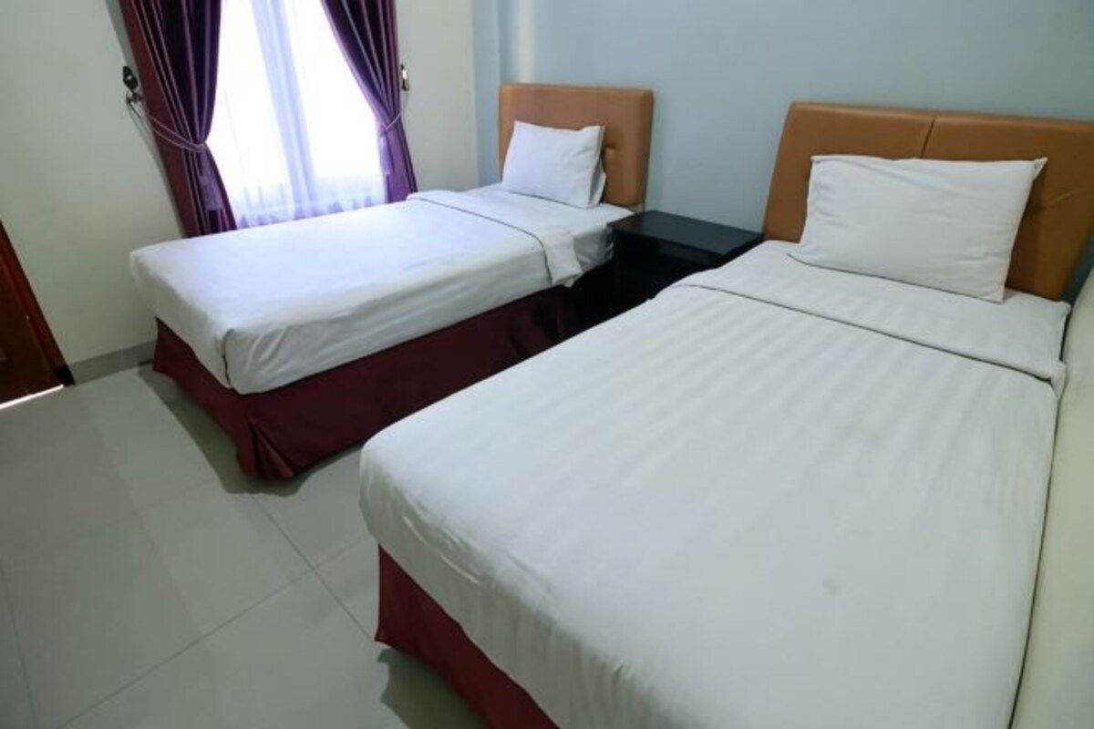 Dos camas individuales con cabeceros de madera en una habitación con ropa de cama blanca.