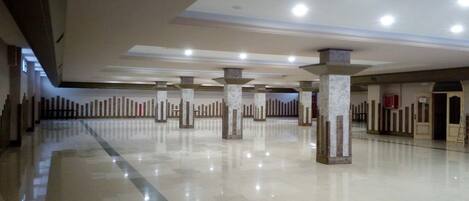 A spacious, well-lit lobby with a polished floor, multiple columns, and a high ceiling.