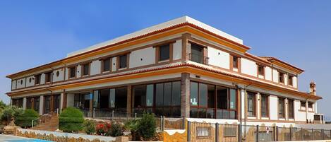 A two-story building with a balcony, large windows, and a pool area.