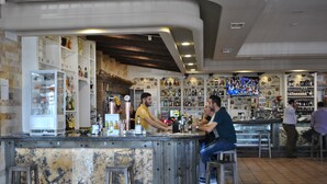 A bar area with a marble counter, stools, and shelves stocked with bottles. - Hotel Restaurante Dama de Baza (Baza)
