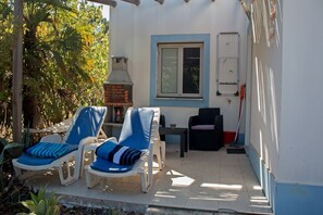 A covered patio area with two blue lounge chairs, a small table, and a brick oven. - Adults Only - Monte Horizonte Casa Mimosa Eco & Nature (Santiago do Cacém)