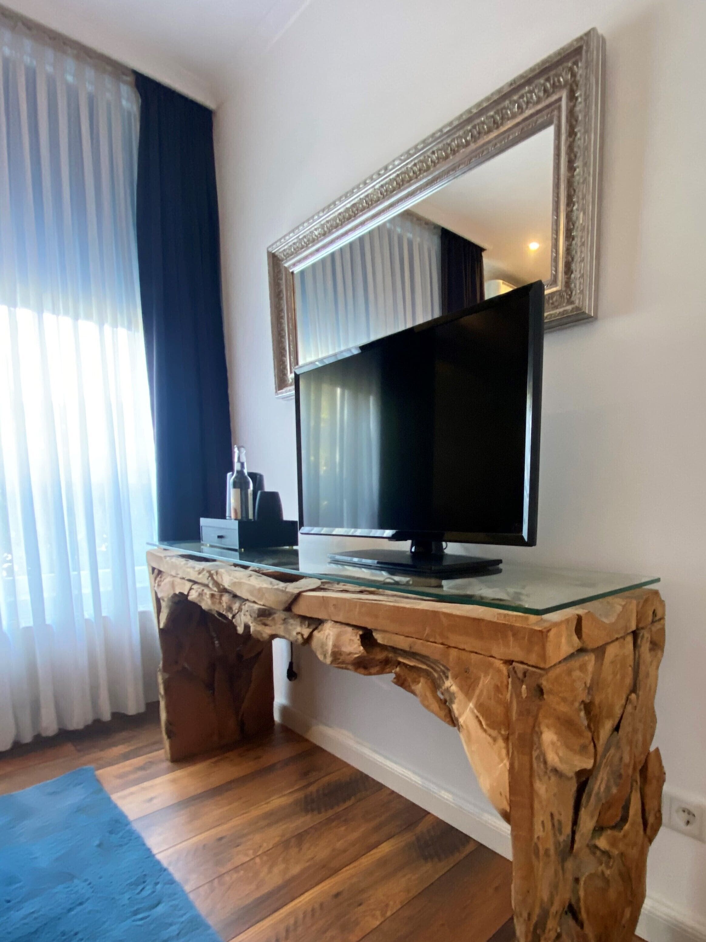 Une chambre dotée d’un bureau en bois, d’un téléviseur à écran plat et d’un grand miroir mural.
