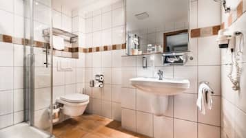 A modern bathroom with a glass shower enclosure, a white sink, and a toilet.