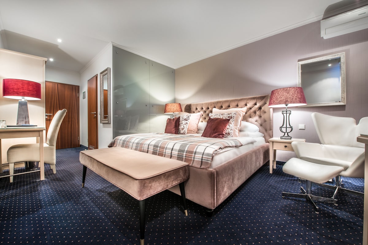 Une chambre d’hôtel comprenant un lit, une table de chevet, une chaise, un bureau et un miroir.