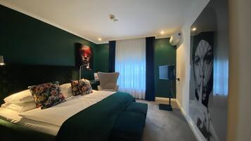Ein modernes Schlafzimmer mit einem großen Bett, einem Nachttisch, einem Sessel und einem an der Wand befestigten Fernseher.