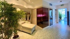 Een moderne hotel lobby met een zithoek, potplanten en een glazen scheiding die naar een kamer leidt.