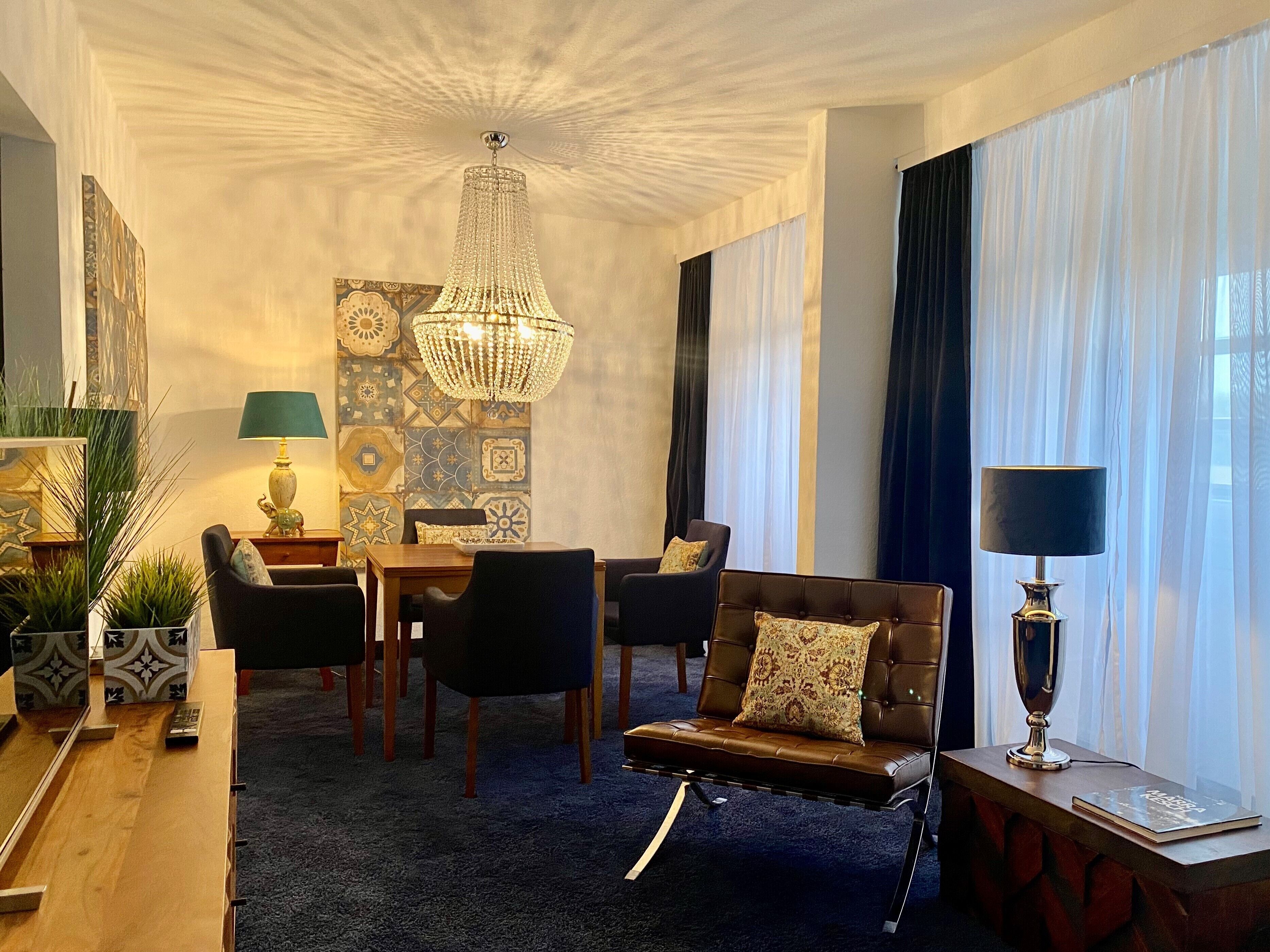A modern living room with a chandelier, a dining table, and a sofa.