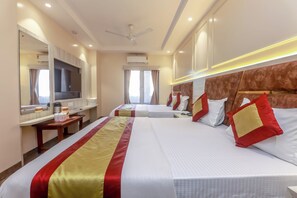 Ein Hotelzimmer mit einem großen Bett, einem Fernseher, einem Schreibtisch und einem Fenster.