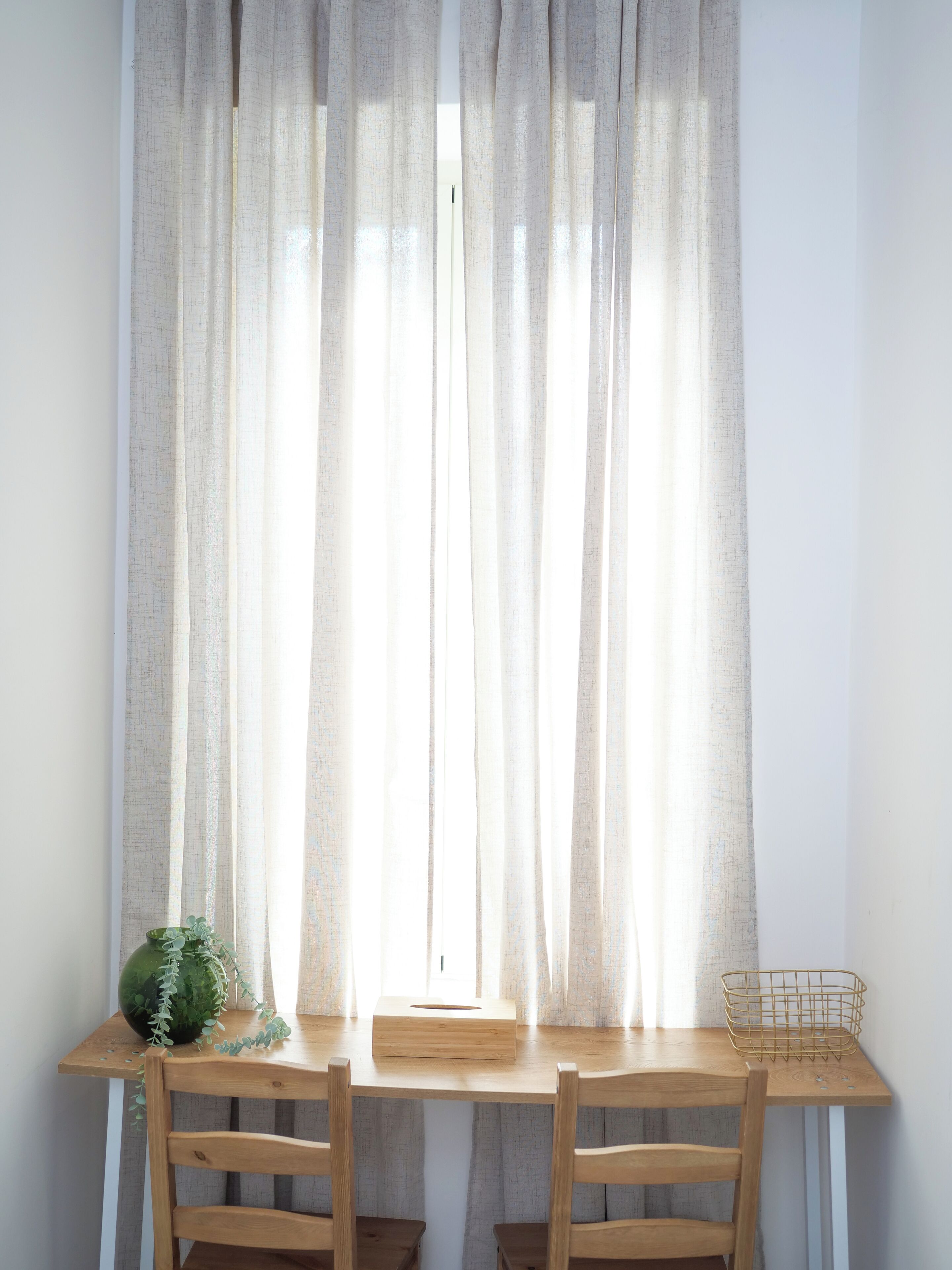 Una mesa de madera con dos sillas, una planta verde, una caja de pañuelos y una cesta de alambre.