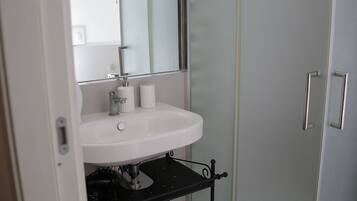 A bathroom with a white sink, a mirror, and a black shelf below the sink.