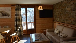 A wooden interior with a dining area, a sofa, a coffee table, and a view through a glass door. - 100 m2 col du Télégraphe 4**** for 10 people in the center of Valloire (Valloire)