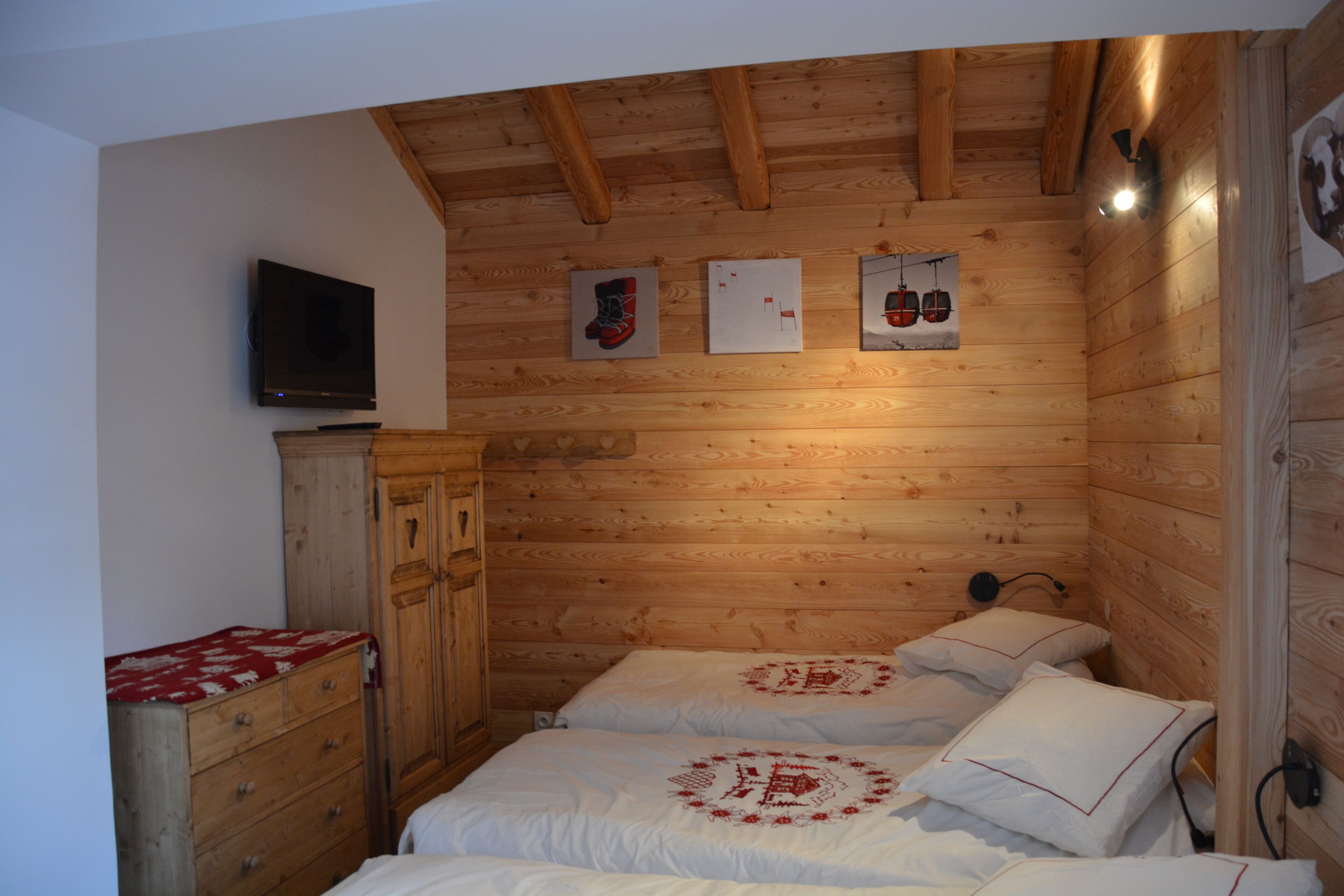 A wooden cabin room with two beds, a TV, and wooden walls.