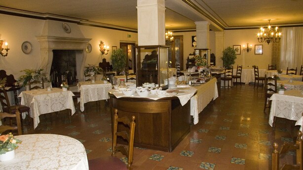 Un comedor amplio con varias mesas, sillas y una isla central con espejo.