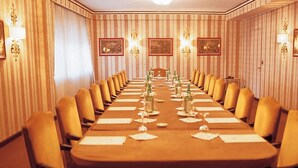 Un salón de conferencias con una larga mesa, sillas amarillas y cuadros en las paredes.