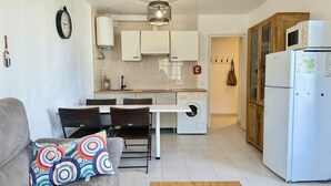 Ein kompakter Wohnbereich mit Essplatz, Küchenzeile und Kühlschrank.