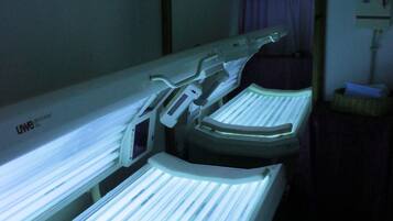 Two treatment beds with control panels and a wall-mounted mirror.