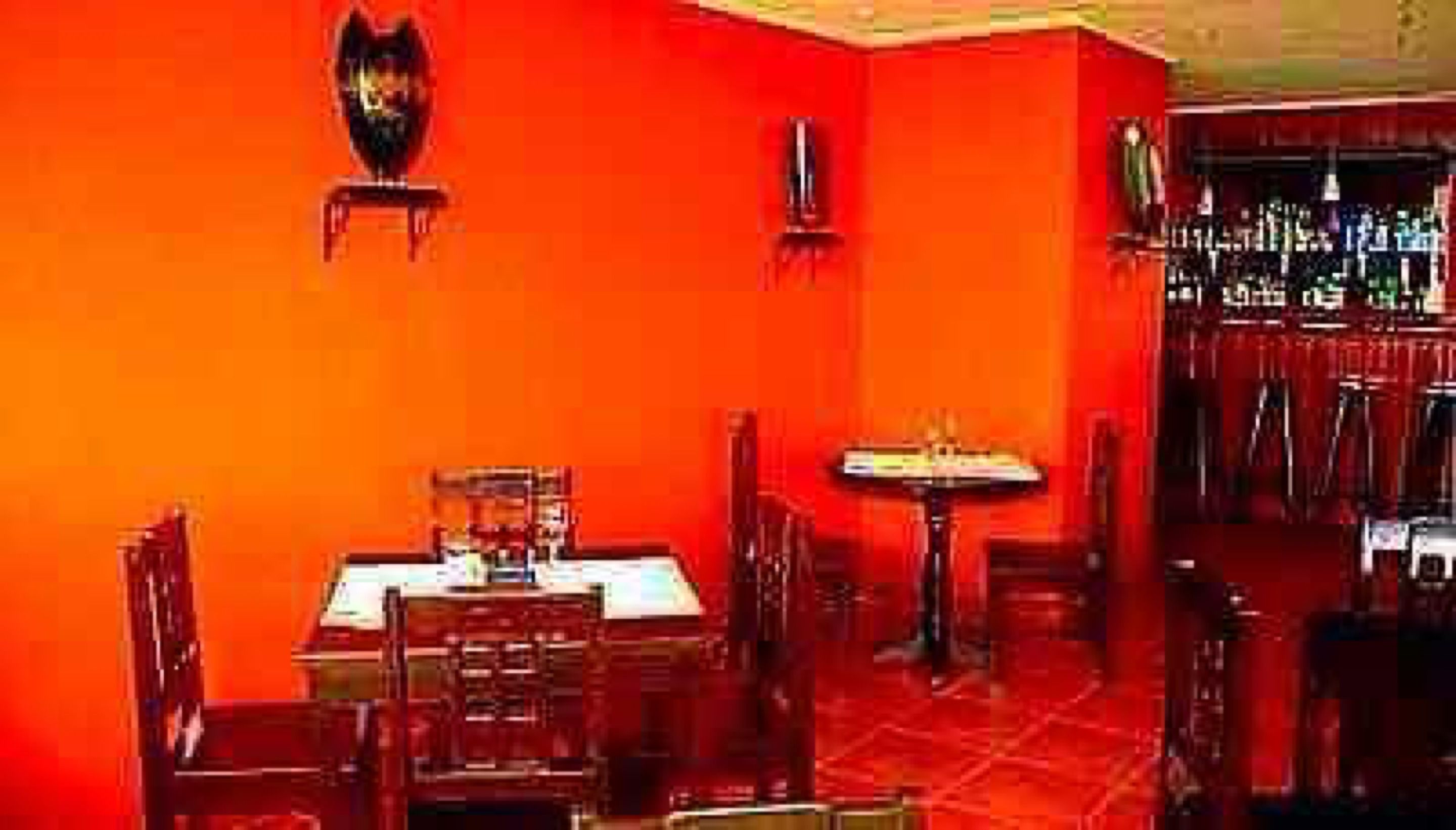 A restaurant with red walls, wooden tables, and chairs.