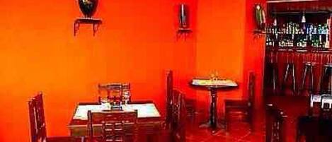 Un restaurante con paredes rojas, mesas y sillas de madera.