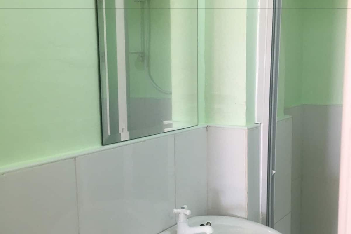 A bathroom with a white sink, a glass shower enclosure, and a mirror.