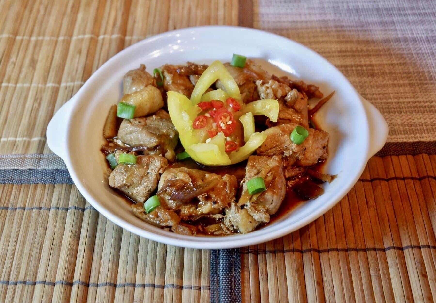 A bowl of food with meat and vegetables on a placemat.