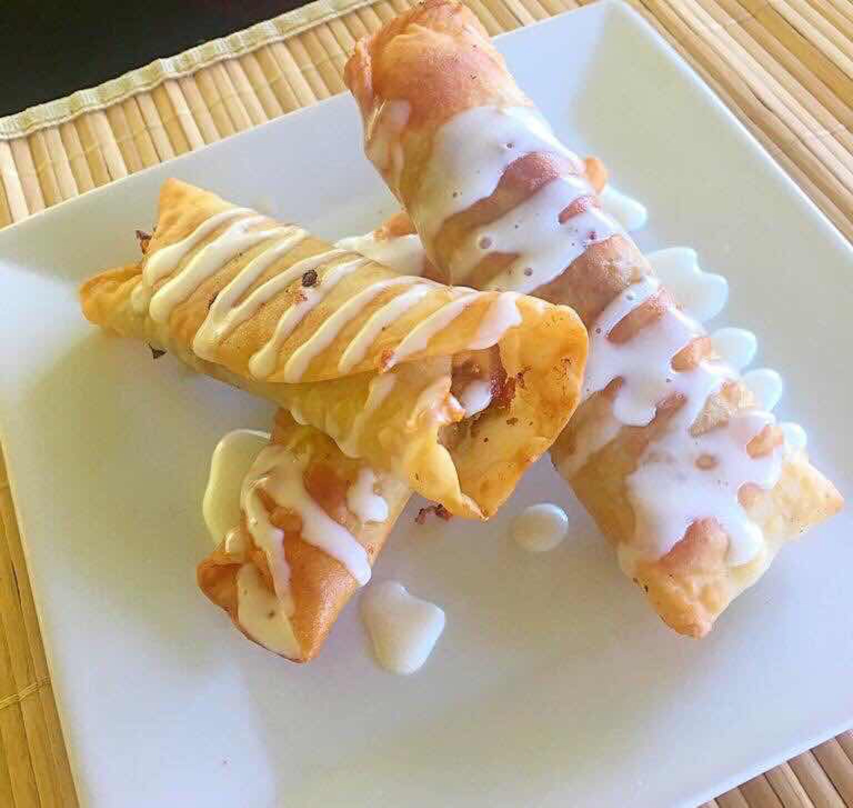 Twee rolkoekjes met witte glazuur op een wit bord.
