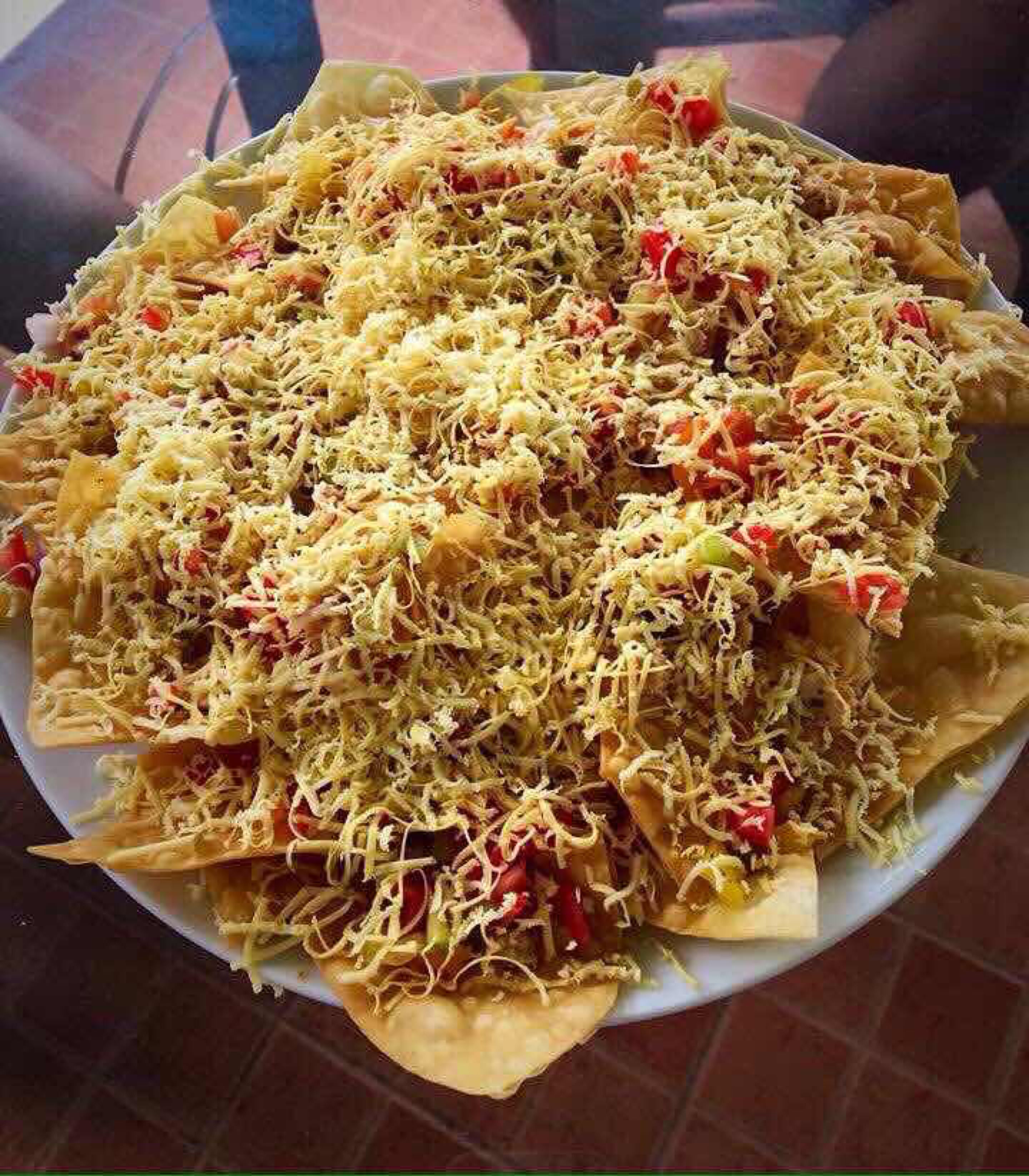 A large plate of food with shredded ingredients and diced tomatoes.