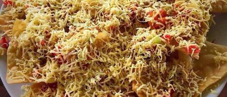 A large plate of food with shredded ingredients and diced tomatoes.