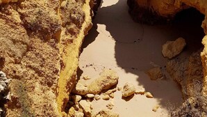 A coastal landscape with a narrow passageway leading to a sandy beach, surrounded by rocky cliffs. - Albufeira Ocean view (62) (Albufeira)