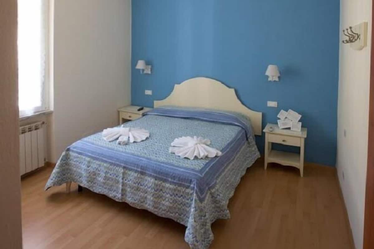 Ein Schlafzimmer mit einem Bett, Deckenventilator, Nachttischlampen und einem Fenster.