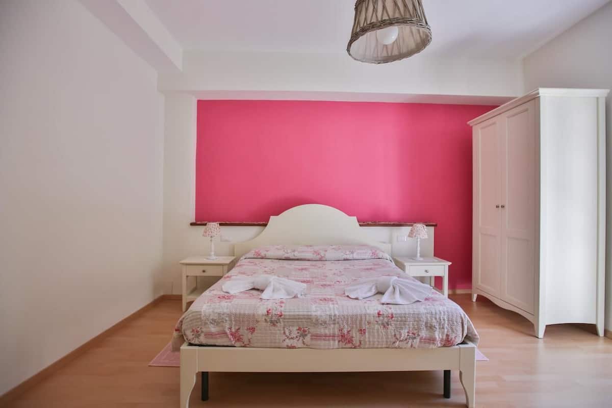 Ein Schlafzimmer mit einem Bett, Nachttischen, einem Kleiderschrank und einer Pendelleuchte.