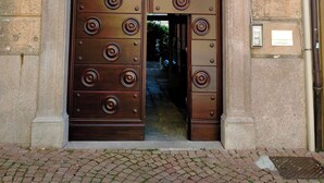 A double wooden door with circular patterns, set in a stone building with a number '30' sign above. - FeWo Luino Loft: Historic Charm, 100m to Lake & Swiss Gateway. (Luino)