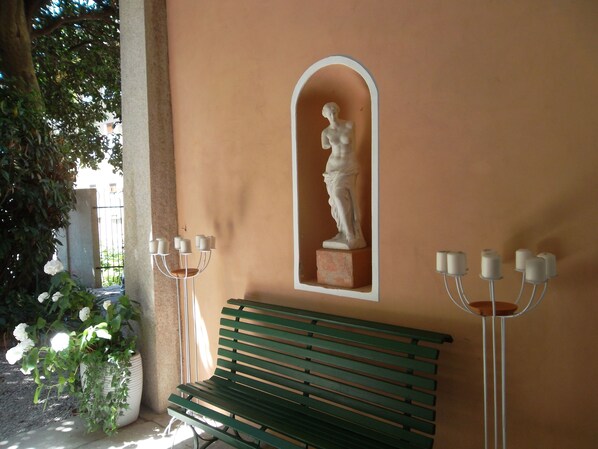 A bench, a wall-mounted statue, and a potted plant.