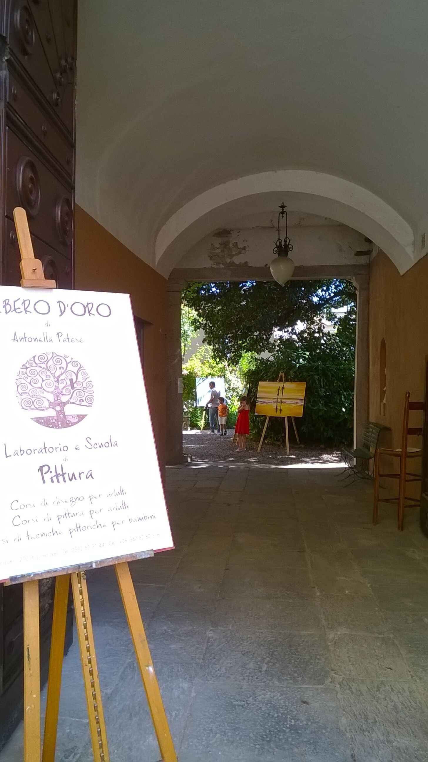 An interior space with an arched ceiling, a wooden easel with a painting, and a signboard with text.