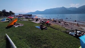 A beach with tents and people relaxing. - FeWo Luino Loft: Historic Charm, 100m to Lake & Swiss Gateway. (Luino)