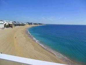 A beach with a clear view of the ocean and a building on the left. - Albufeira, Ocean terrace (22) by Rentals in Algarve (Albufeira)