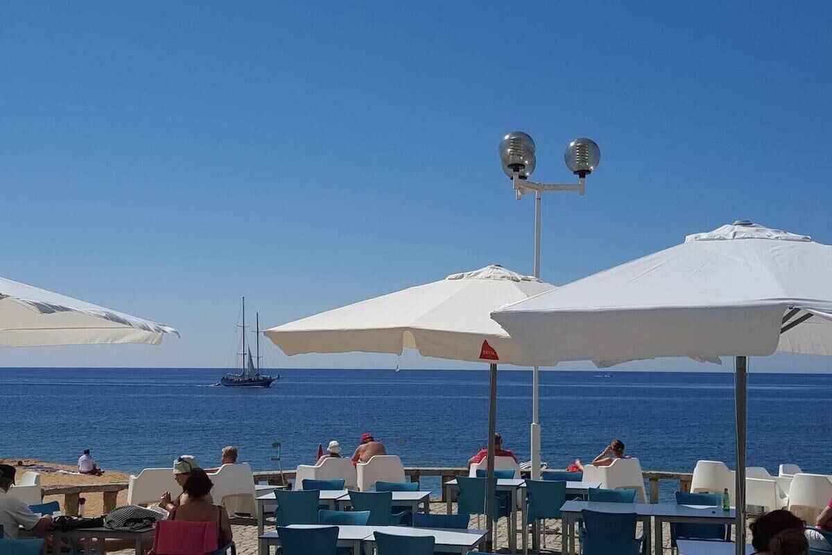 A beachside café with outdoor seating and umbrellas, overlooking the sea.