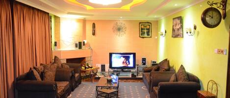 A living room with a television, sofas, a coffee table, and a decorative wall clock.