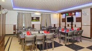A conference room with tables and chairs, a television, and a patterned ceiling.