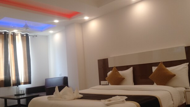 A hotel room with a large bed, a bedside table, a desk, and a chair.