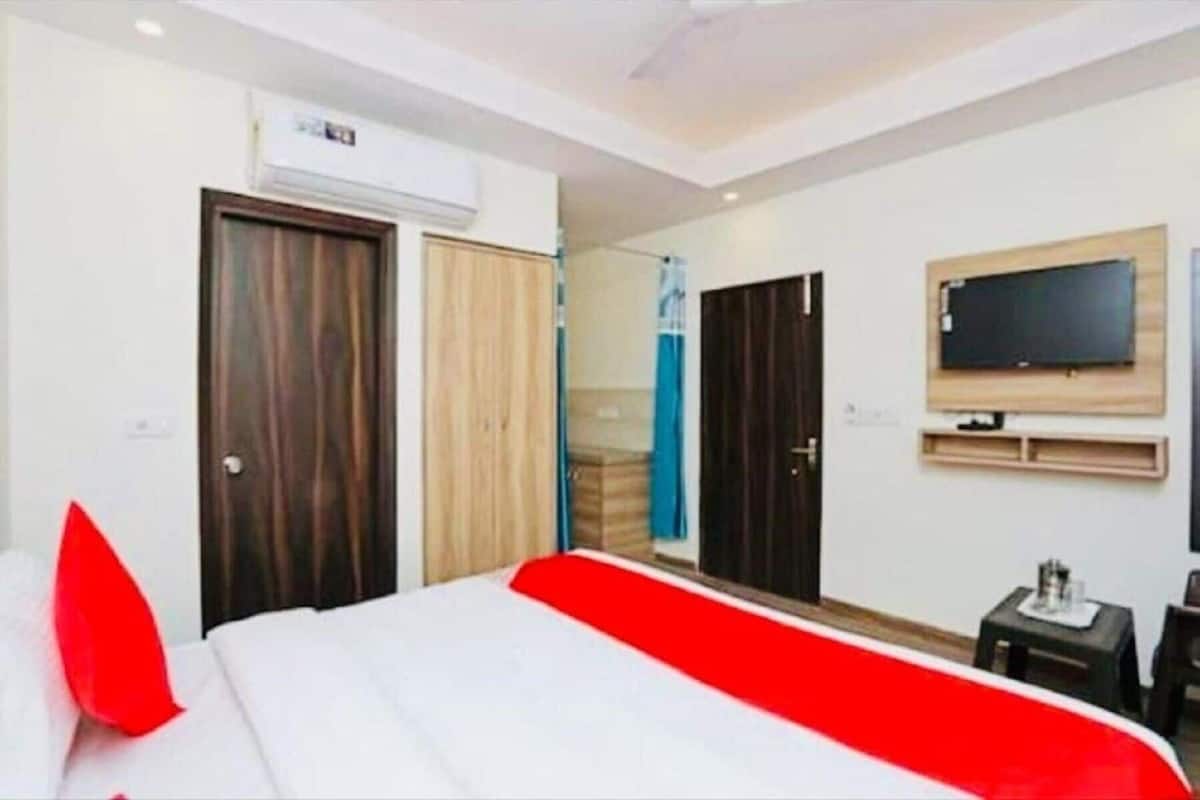 Une chambre d’hôtel avec un lit, un téléviseur fixé au mur et une porte.