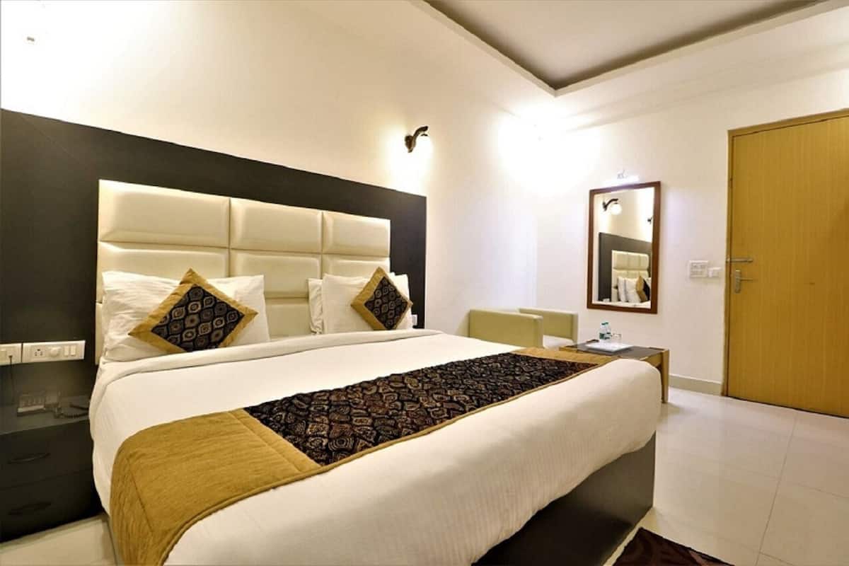 Une chambre d’hôtel avec un grand lit, une table de chevet, un miroir et une porte en bois.