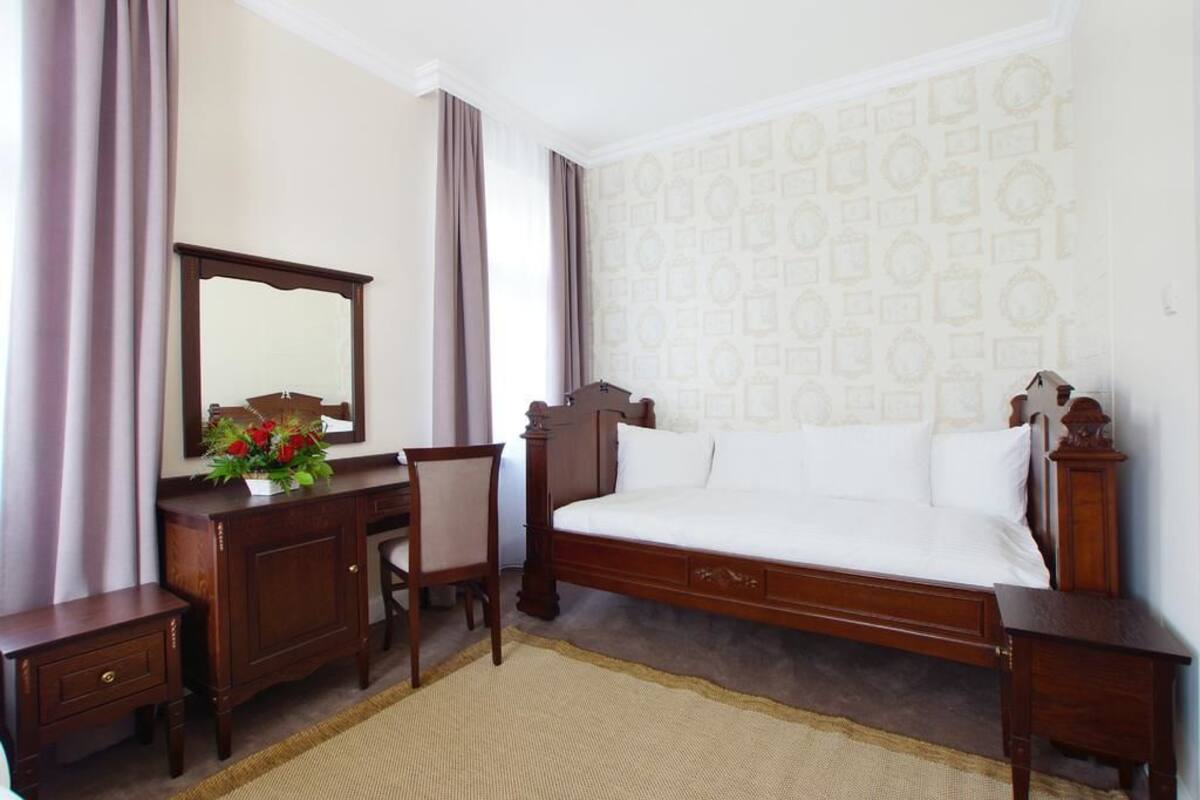 A bedroom with a wooden bed, a desk, a chair, a dresser, and a mirror.