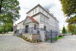 A large, multi-story building with a stone facade and a red-tiled roof. - Villa La Pierre (Strzegom)