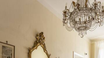 A room with a fireplace, candles, a chandelier, and a patterned floor.