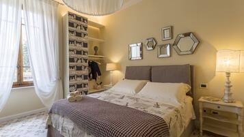 A bedroom with a bed, a wardrobe, a nightstand, and a window with curtains.