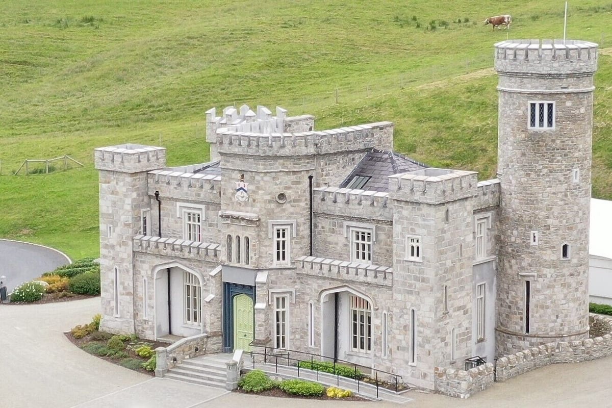 A castle-like building with a central tower, multiple windows, and a green door.