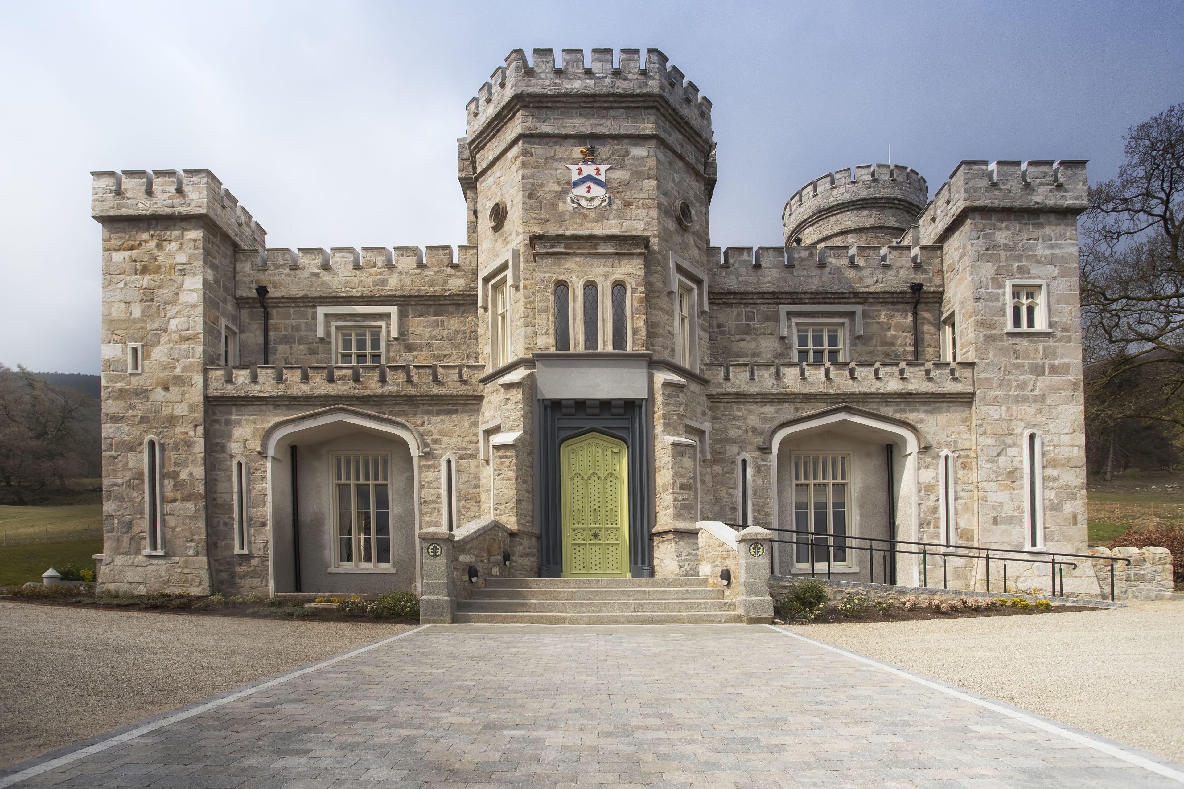 Un bâtiment qui ressemble à un château, avec une tour centrale, des fenêtres en arc de cercle et une porte verte.
