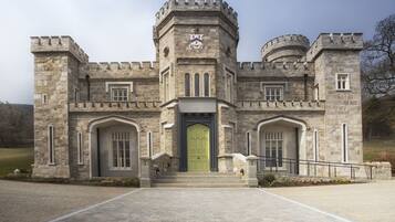 Un bâtiment qui ressemble à un château, avec une tour centrale, des fenêtres en arc de cercle et une porte verte.