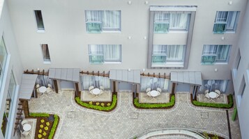 Un patio con mobiliario exterior, varias ventanas y un jardín central.