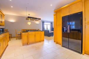 Una cocina moderna con armarios de madera, un refrigerador negro y una isla central con estufa.